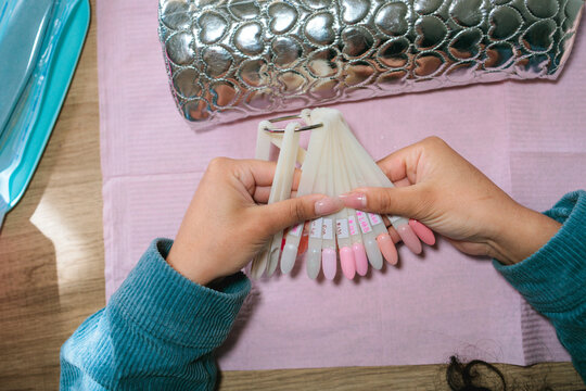 Woman chosing gel polish color from nail palette