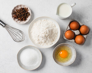 Baking ingredients flat lay with flour, eggs, sugar, and spices on marble surface