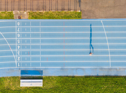 Aerial View of Blue Running Track with Runner Long Shadow at Daw