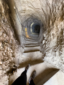 Anonymous feet on a staircase leading to a cave tunnel
