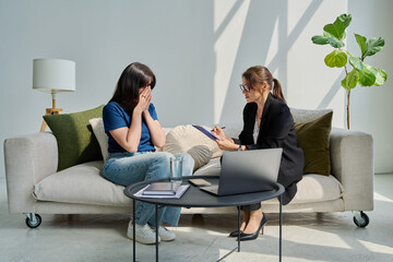 Sad unhappy woman in therapy session with female psychologist