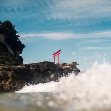 Torii gate on rocky coastline with waves