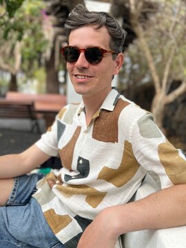casual young man relaxing under trees in urban setting