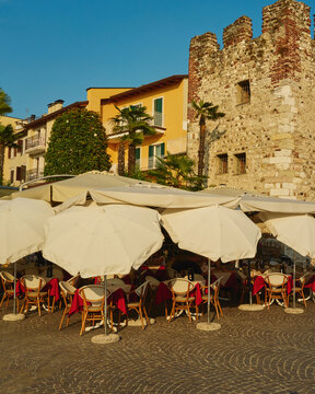 Outdoor Dining Under Umbrellas Near Historic Stone Tower