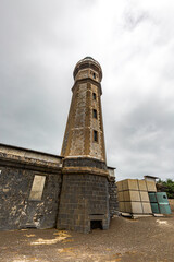 Fototapeta premium Faial, Azores, island, Portugal, Lighthouse is tall and leaning to the right. The sky is cloudy and the lighthouse is surrounded by a lot of buildings