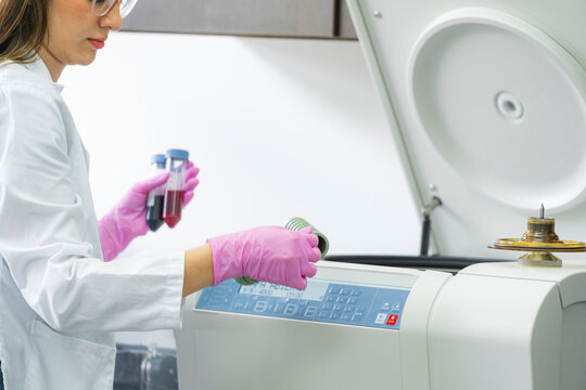 Scientist using centrifuge machine with blood samples in laboratory
