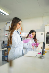 Fototapeta premium Two female scientists working in laboratory with liquid samples