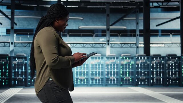 Smiling data center technician using tablet to manage software updates for system stability. Upbeat IT expert in server room configuring infrastructure with device for optimum performance, camera A