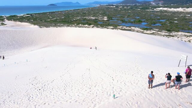 Aerial view of the dunes of Joaquina Beach in Florian&oacute;polis, Santa Catarina. People surfing on the sand, sandboard, sports, dune fields, restinga vegetation, ecological and tourist lagoons