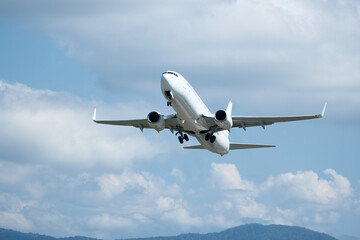 White plane climbing higher against the clouds. Airplane flying in the blue sky, take-off from airport
