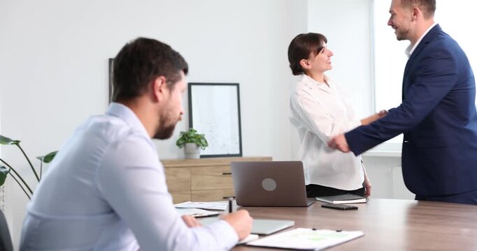 Man feeling jealous of his successful colleague receiving congratulations in office