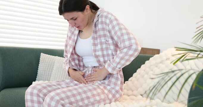 Woman suffering from cystitis symptoms on sofa at home
