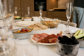 Close-up of a festive dining table with bread, cured meats, vegetables, and olives served in bowls, symbolizing sharing, celebration, and homemade family meals.