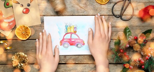 Naklejka premium Female hands with beautiful Christmas card and decor on wooden background, closeup