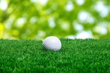 Golf ball on green grass against blurred background