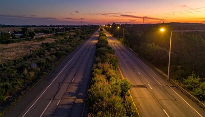 Fototapeta premium Generated image : Wide shot from above of a deserted highway at dusk, broken streetlights casting long shadows, overgrown with weeds, somber mood, photorealistic.