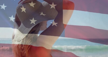 Standing adult woman wearing straw hat and red swimsuit at water's edge, with American flag overlay