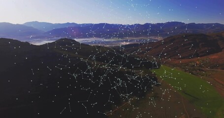 Spanning digital node-and-line network overlaying valley farmland at dusk, with data visualization