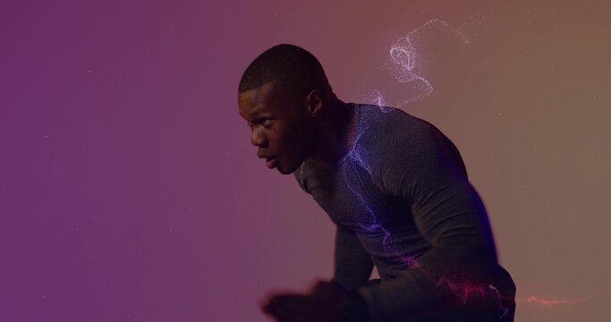 Leaning male athlete in compression shirt catching breath in studio, with gradient particle swirls