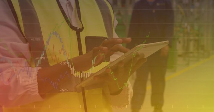 Male worker wearing safety vest using touchscreen tablet in plant, with yellow floor markings