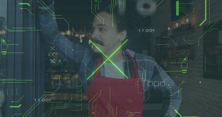Leaning cafe worker wearing red apron and plaid shirt looking outward in cafe, with digital overlay