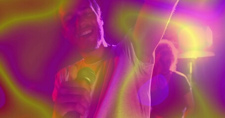 Singing singer holding mic and raising arm on club stage with colorful spotlights and lens flare