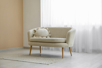 Comfortable sofa with carpet and light curtain in interior of living room