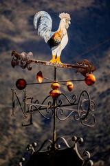 A weather vane with a rooster on top and the letters N and Q on the bottom