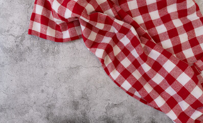 Top view of a red and white checked tablecloth in a corner of a gray surface
