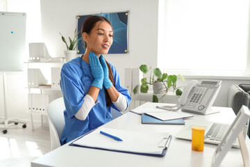 Female Asian endocrinologist video chatting at table in clinic
