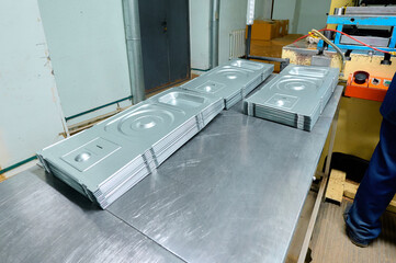 Cold metal stamping parts stacked on a workbench in a manufacturing facility