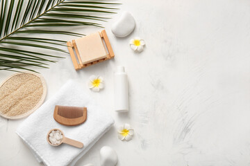 Spa composition with stones, towel, tropical leaf and plumeria flowers on white background, closeup