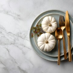 Elegant table setting with small white pumpkins, gold cutlery, and decorative sprigs on a light ceramic plate, perfect for autumn or Thanksgiving dinner decor