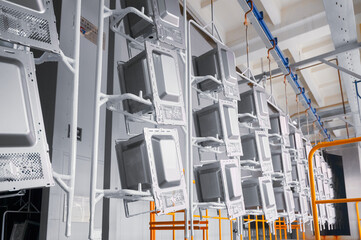 Powder coating workshop with microwave oven casings on conveyor during washing stage in an...