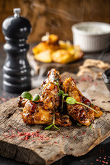 Hot grilled chicken wings with herbs on rustic board