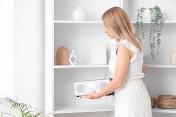Obraz premium Female interior designer putting radio receiver on shelf in living room