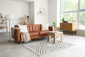 Interior of stylish living room with brown sofa, shelf units and plants