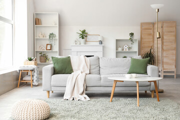 Interior of stylish living room with grey sofa, shelf units and plants