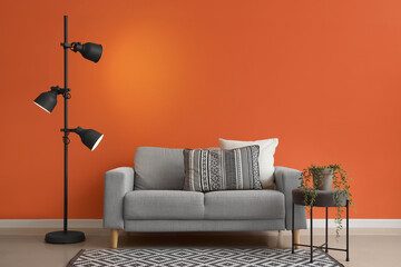 Interior of stylish living room with cozy grey sofa, coffee table and glowing standard lamp near...