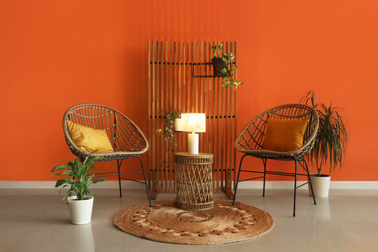 Interior of stylish living room with chairs, houseplants and glowing lamp on coffee table