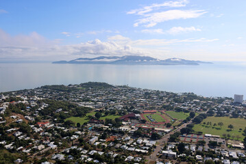 Aerial view of Townsville with houses, roads, a sports field and Magnetic Island in the background in Queensland, Australia