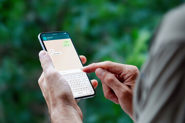 Man holding a mobile phone showing a chat app on the screen. Communication technology, apps.
