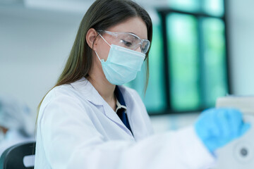 A histotechnologist dons sterile nitrile gloves, following aseptic technique and safety protocols before operating a microtome to section tissue specimens in a pathology laboratory.