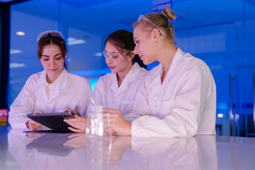 A diverse team of researchers in a biotechnology lab reviews preliminary data from an experiment on a tablet. They are collaborating on the next phase of their R&D project.