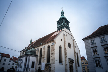 Obraz premium Exterior view of the Franciscan Church, or Franziskanerkirche, in Graz, Austria, showing the nave, tower, and Gothic elements of the historic monastery church situated in the old town.