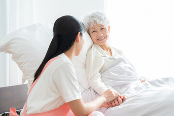 Obraz premium 高齢者を介護する若い女性介護士