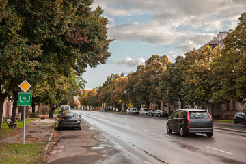 Road signs on Londoni Korut in Szeged, Hungary, show the green shield for Main Road 5 alongside a priority diamond. a typical urban hungarian road with a car driving and passing fast.