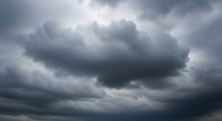 Obraz premium A dark and turbulent mass of heavy grey storm clouds gathers in the sky, heralding an approaching thunderstorm. A moody weather background.