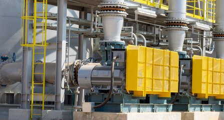 Powerful industrial pumps operate in a manufacturing facility. Yellow safety barriers protect the machinery while ensuring efficient performance and safety