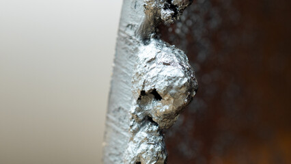 A detailed view of a metallic surface reveals significant corrosion and unique textures. The image...